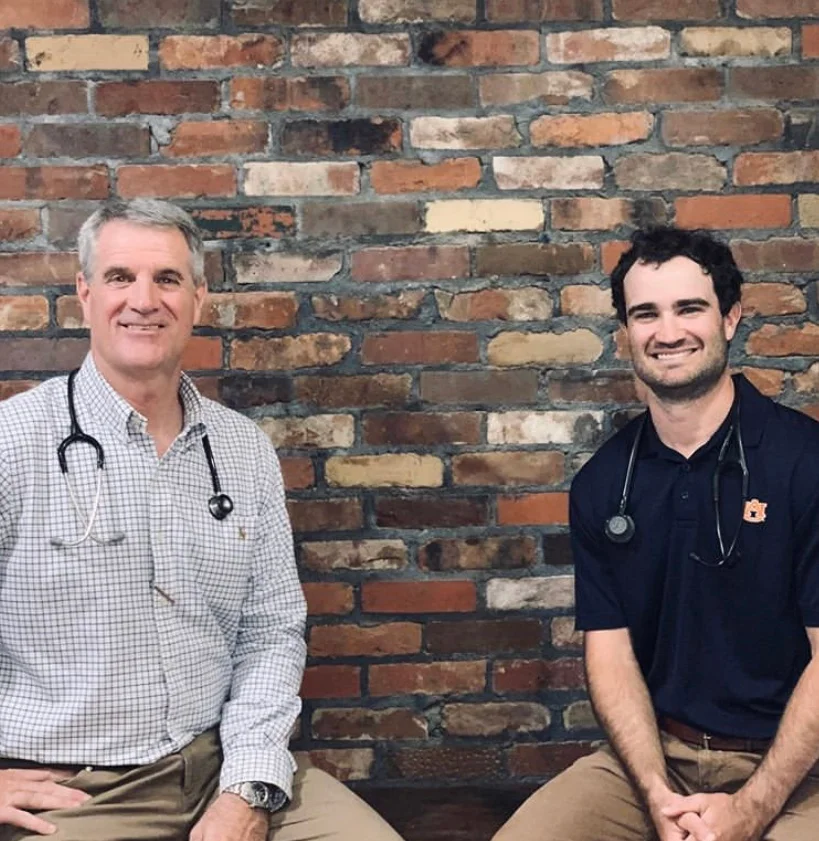 Dr. Robert Hawkins and Dr. Douglas Hawkins, the veterinarians of Troy Animal Clinic, standing against the clinic's brick wall